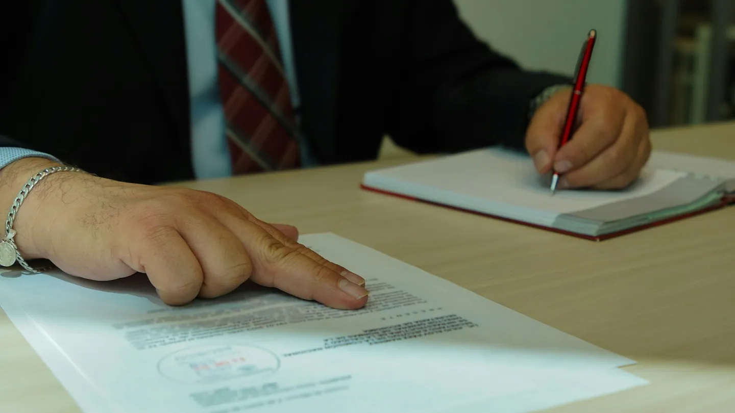 Una persona firma un documento con un bolígrafo.